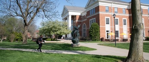 Student walking near Crounse Hall in springtime