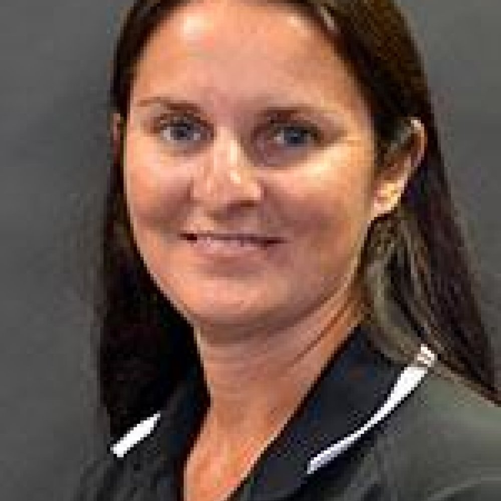 Lisa Owens headshot, lady with dark long hair wearing Centre logo athletic polo shirt in front of grey background