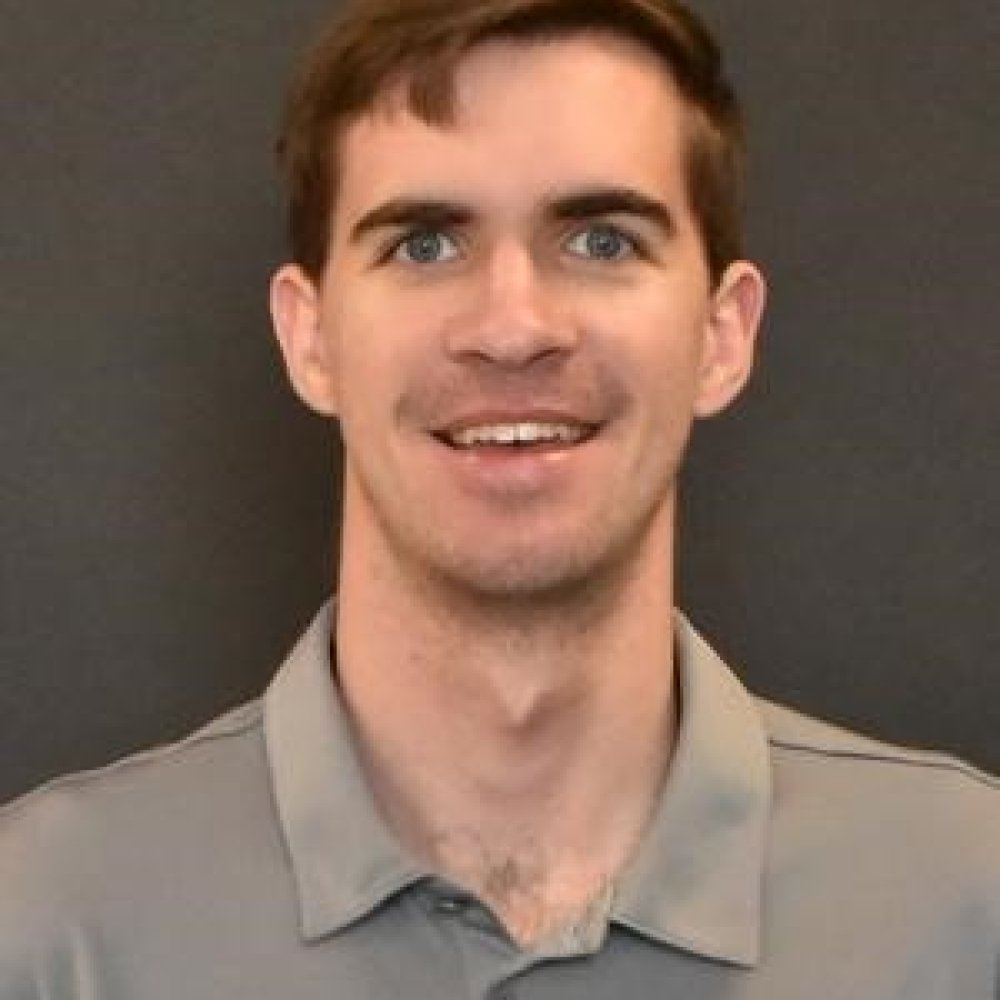 Matthew Wentz headshot, man with short brown hair wearing grey Centre logo athletic polo shirt in front of grey background