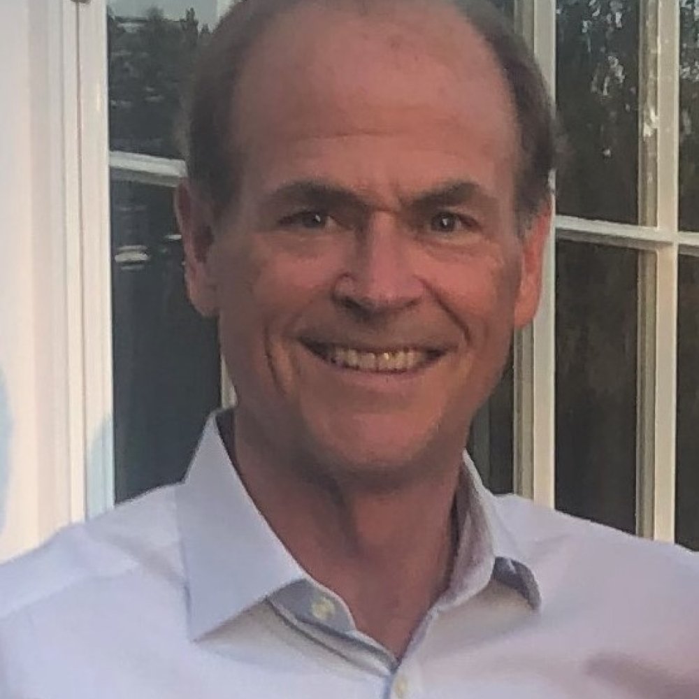 Man with dark hair wearing light grey button up shirt