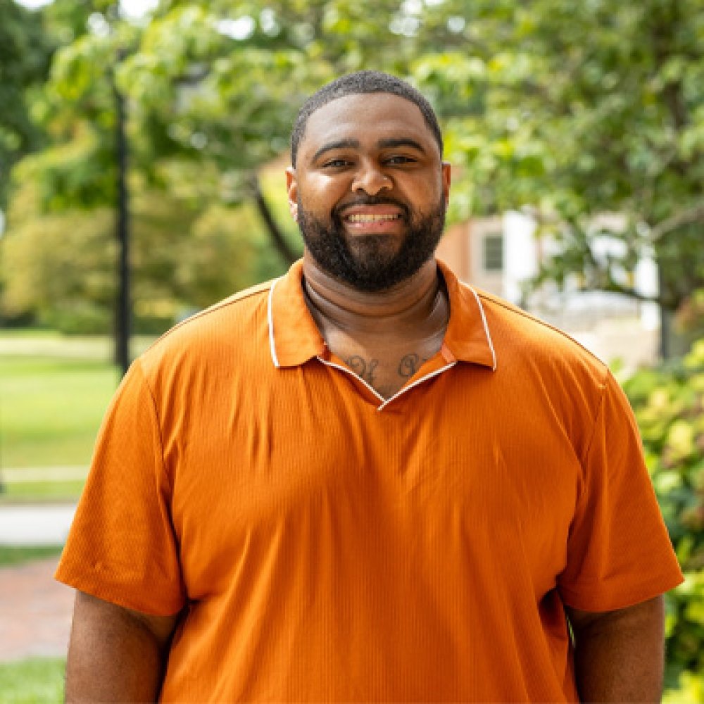 Person wearing an orange polo shirt and smiling at camera