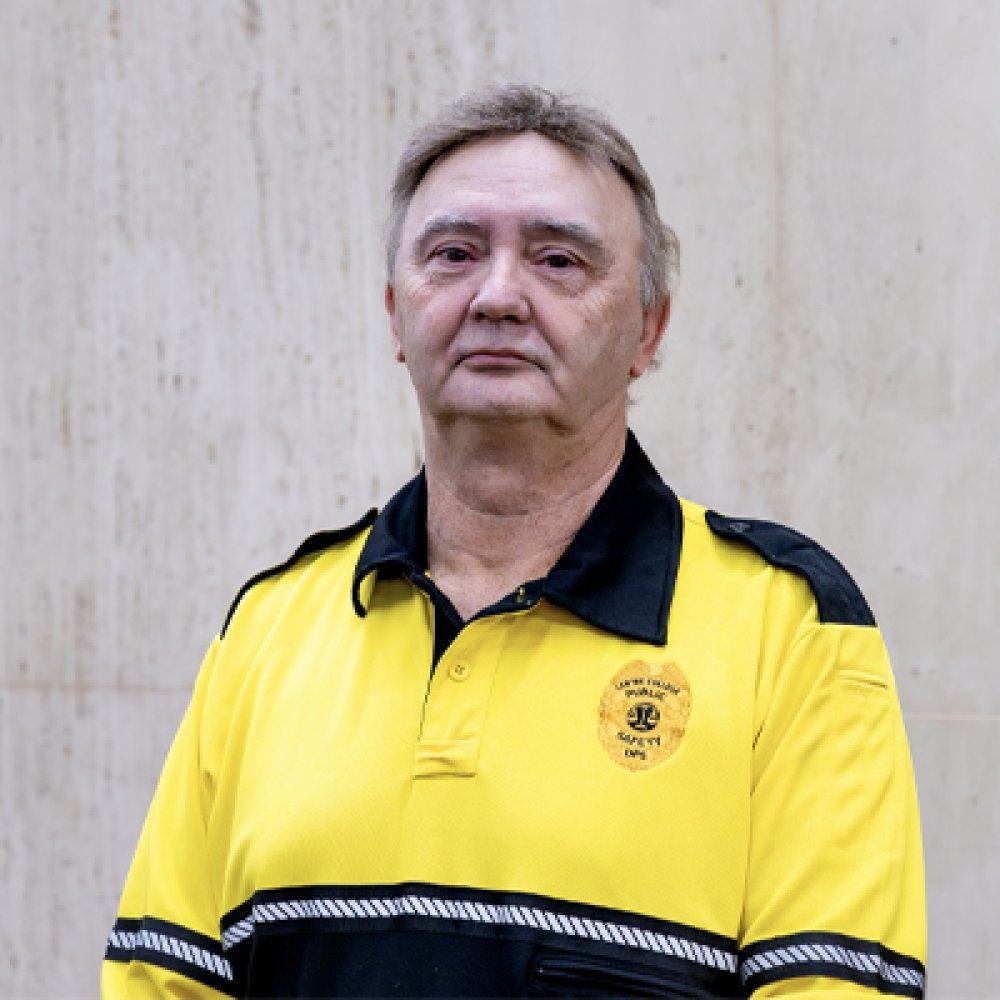 Person wearing gold and black polo top with DPS badge logo