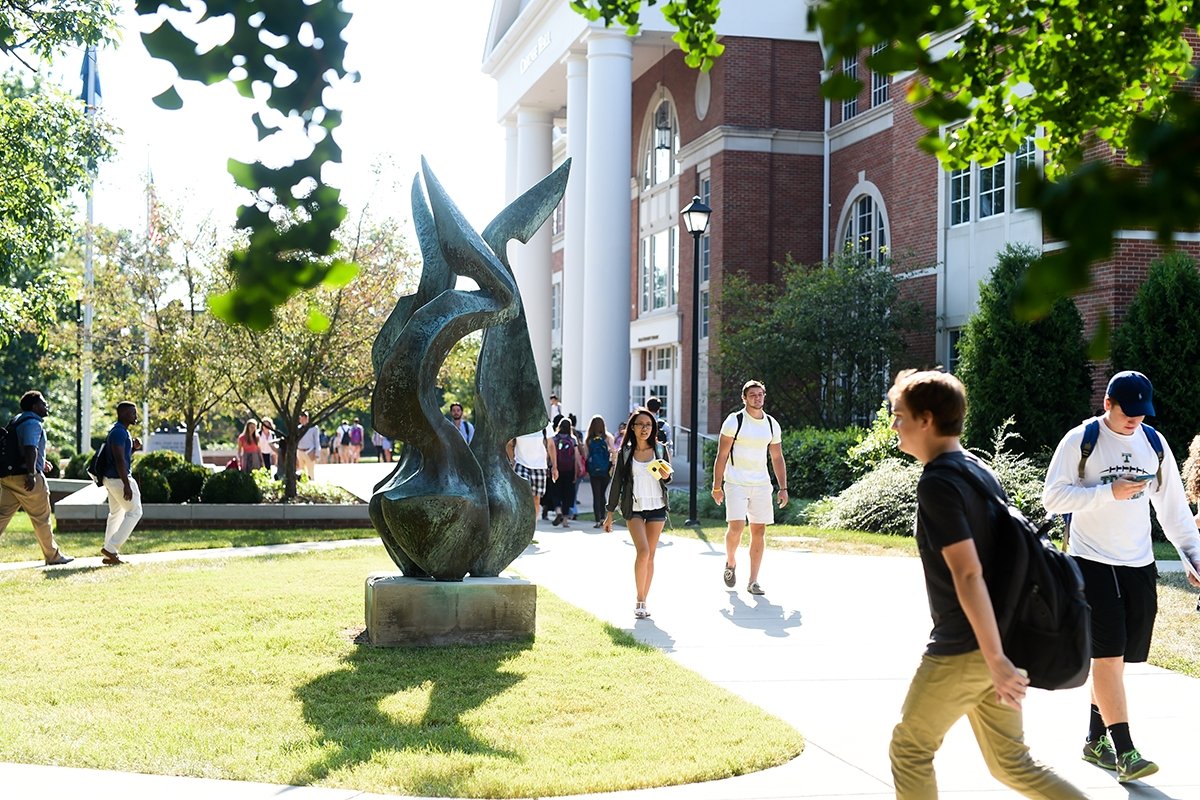 Students walking near the Flame statue on campus