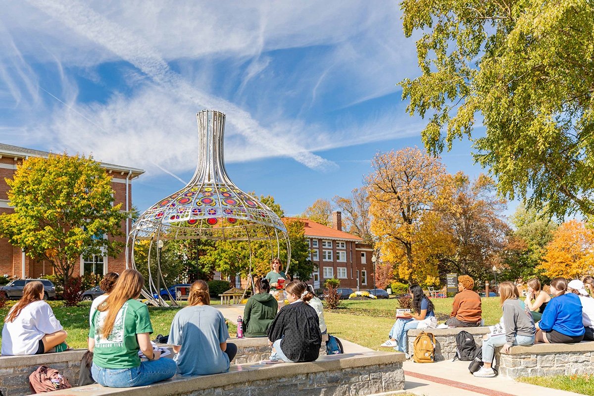 Outdoor classroom with students sitting listening to professor in front of Stephen R. Powell memorial 