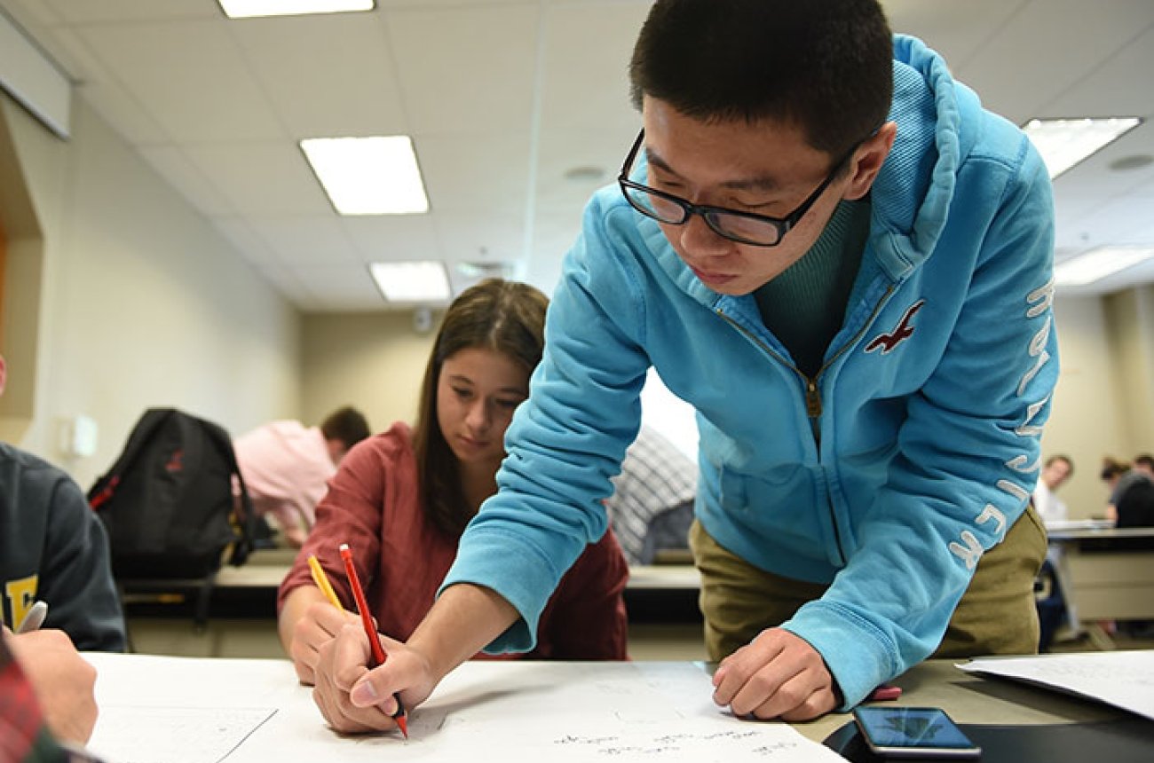 Student writing data on large layout