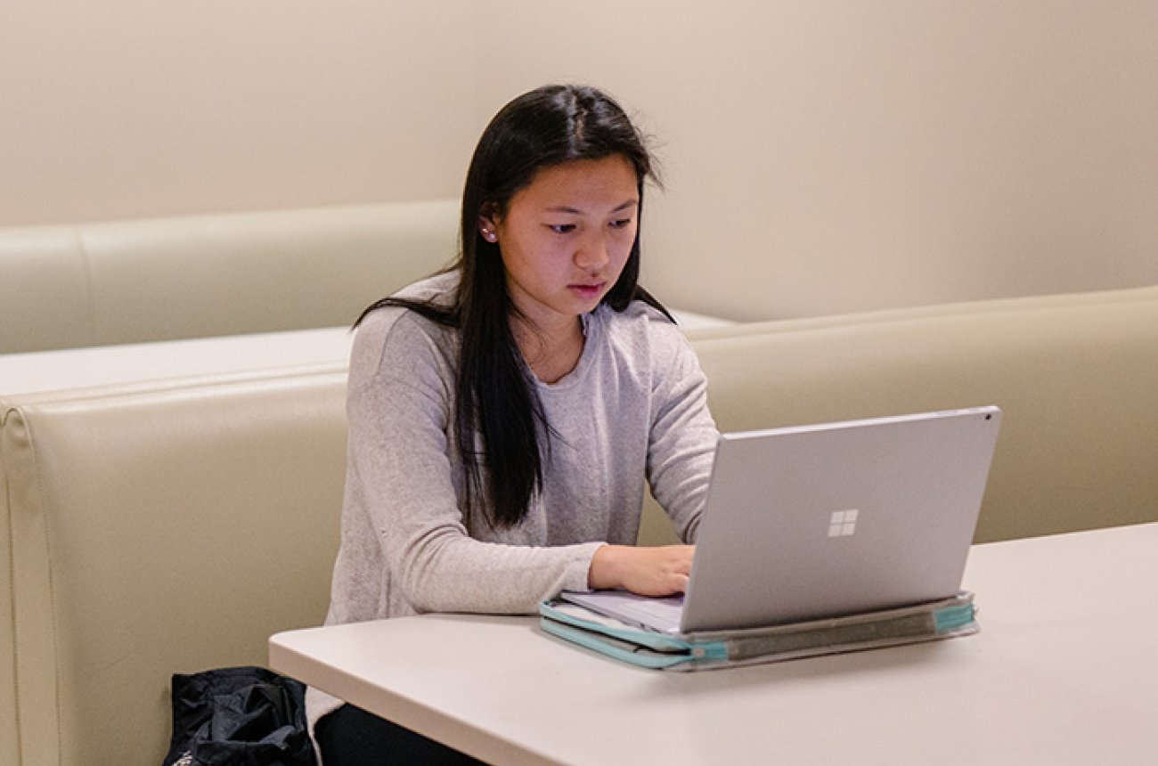 Student using a laptop seated at a table
