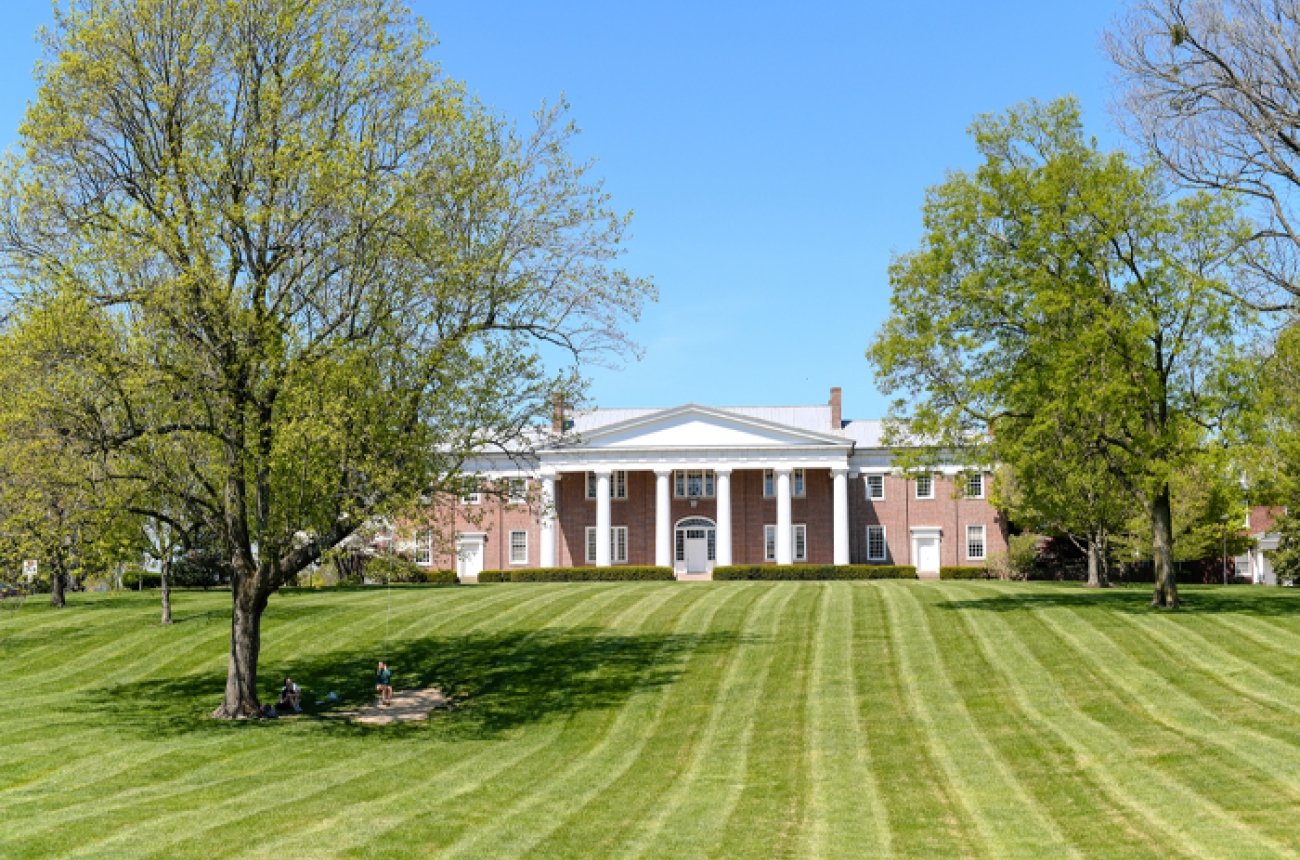 Old Centre building in with bright green grass and two green trees in front of building