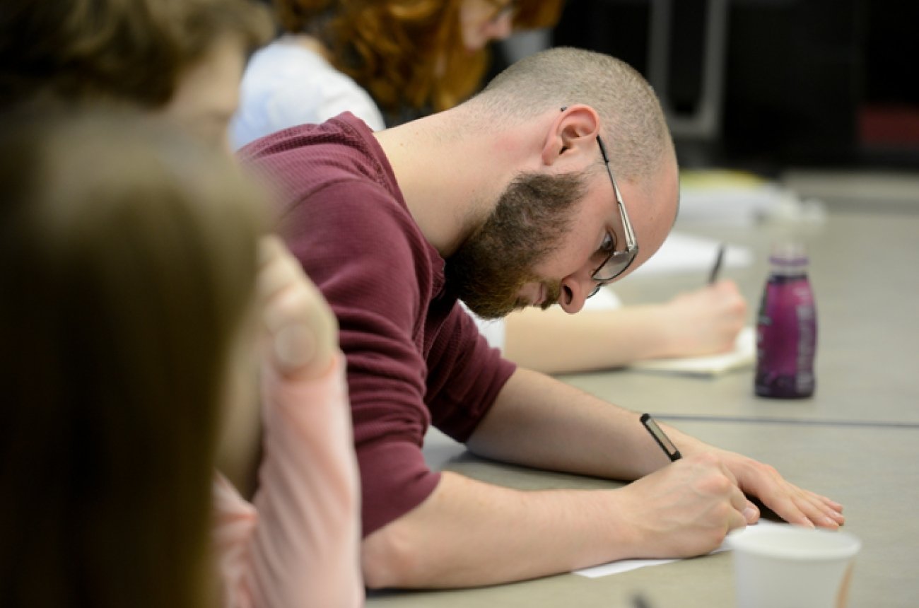 Man taking notes in class wearing glasses