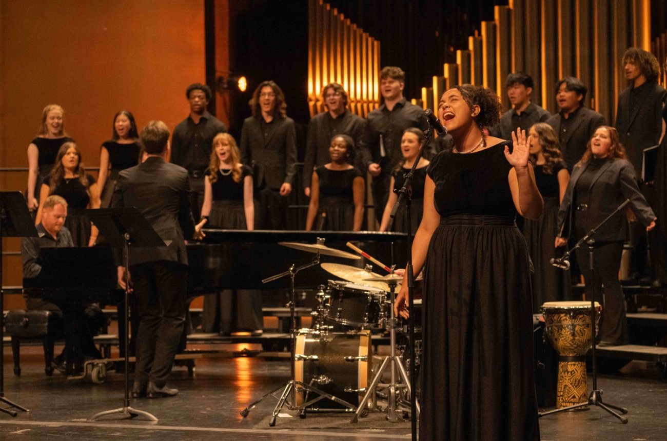Student singing a solo in front of choir in background