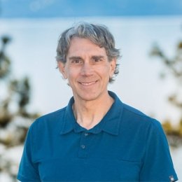 Man with grey hair wearing blue polo in front of outdoor background in Tahoe