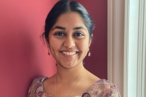 Headshot of Kevli leaning on a wall and smiling into the camera