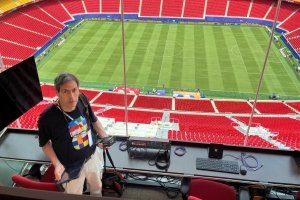 Dave standing behind an IT desk, with the Kansas City field behind him.