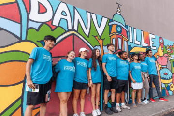 First year students stand in front of downtown mural with many colors and "DANVILLE" in bold.