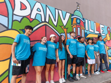 First year students stand in front of downtown mural with many colors and "DANVILLE" in bold.