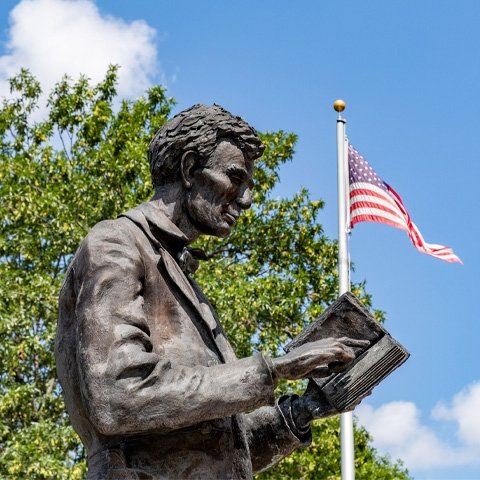 Abraham Lincoln statue in front of Crounse with the American Flag flying in the background