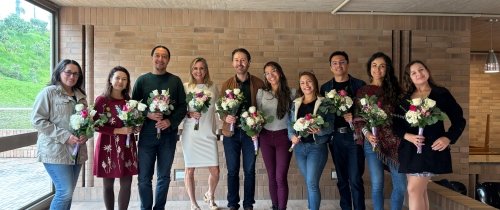 A group of men and women pose for a photo together, each holding a bouquet of flowers.