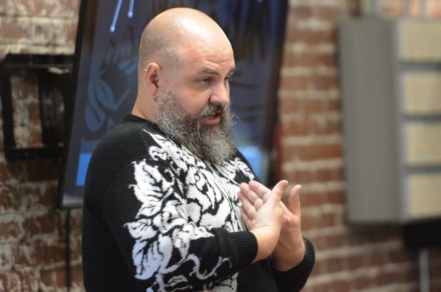 A man gestures to himself as he speaks to others.