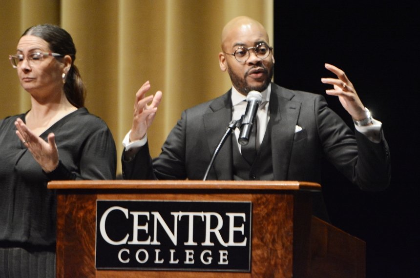 A man speaks into a microphone mounted to a lectern bearing the name Centre College.