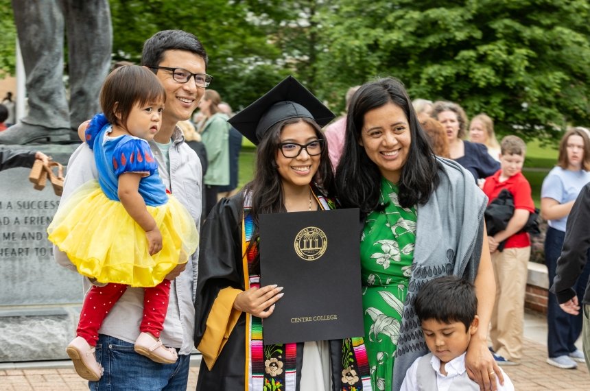 A family of 5 pose for a photo with their graduate