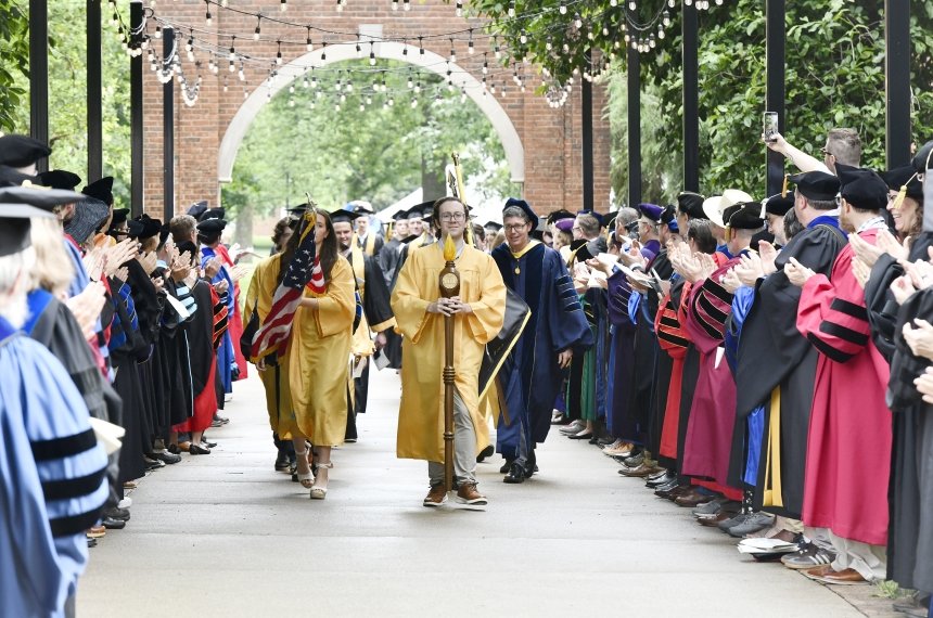 Logan Ward leads the procession of graduates between lines of clapping faculty.
