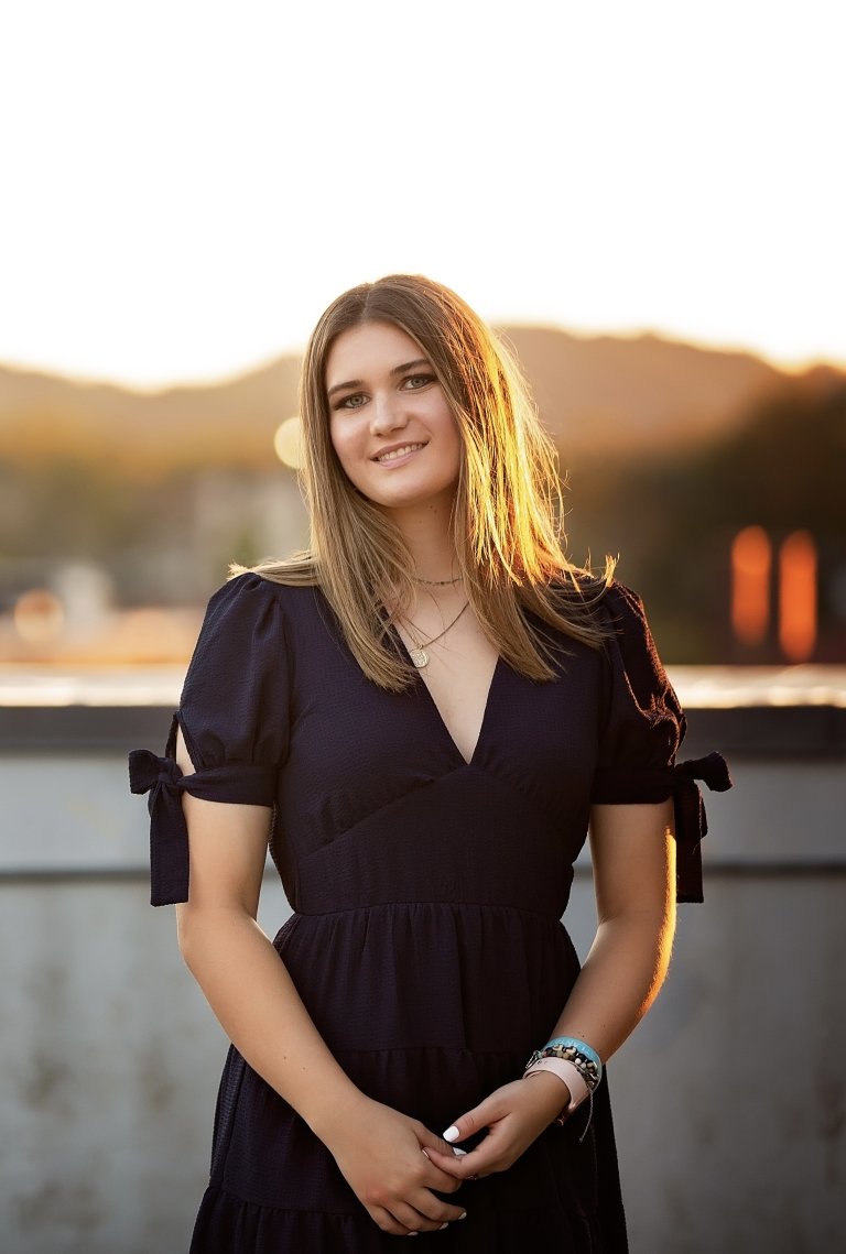 A young woman poses for a photo in a black dress. 