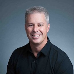 Person wearing black shirt in front of grey background smiling 