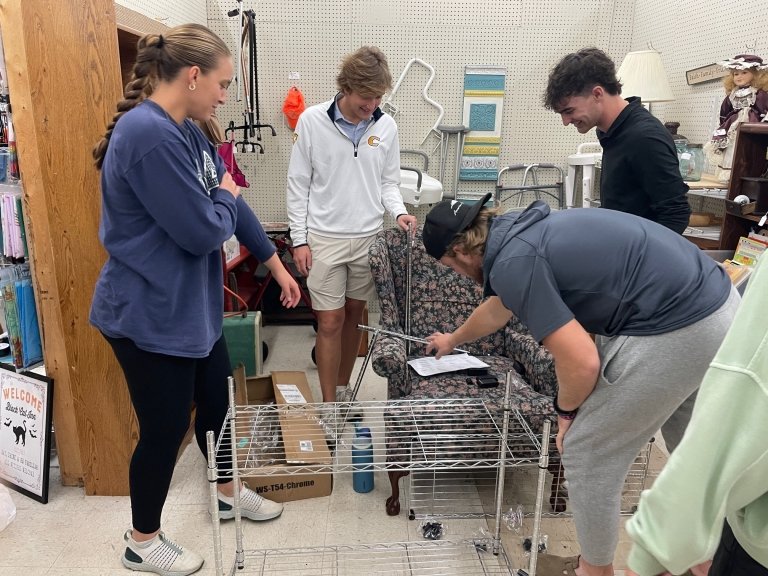Four students work together to assemble metal shelving for product display. 