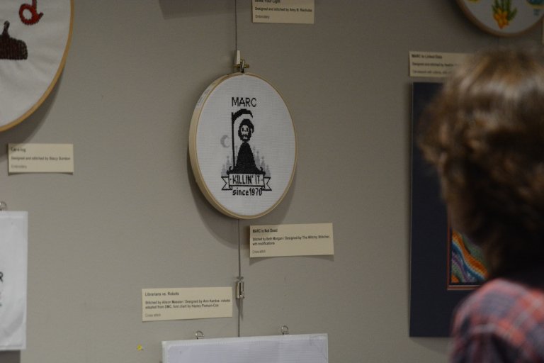 Beth Morgan ’01 talks about the Unseen Labor exhibit at Centre’s Grace Doherty Library as students and staff examine the work on display.  