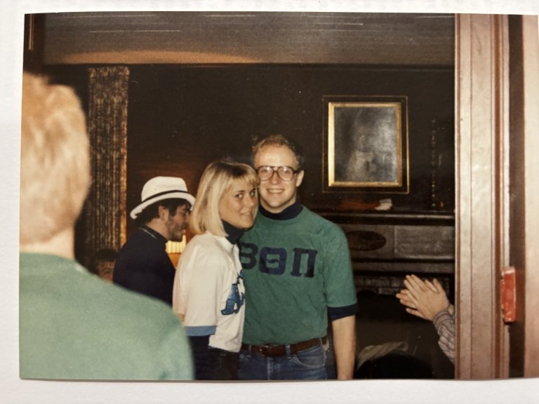 An archive photo shows a young woman and young man hugging during a social gathering at a home. 