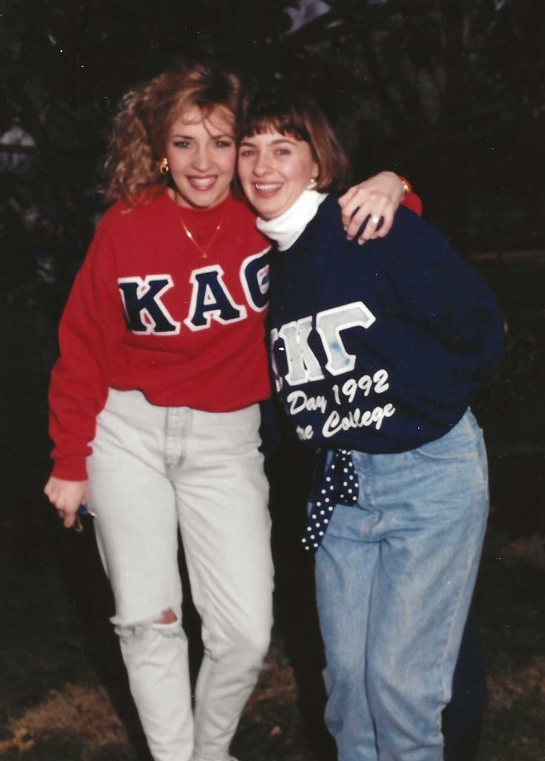 This archive photo shows two young women hugging for the camera, both wearing sorority sweatshirts. 