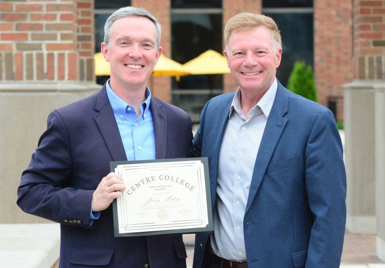 A man holding a certificate of recognition poses for a photo with Centre President Milton C. Moreland. 