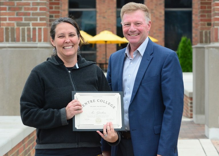 A woman holding a certificate of recognition poses for a photo with Centre President Milton C. Moreland. 