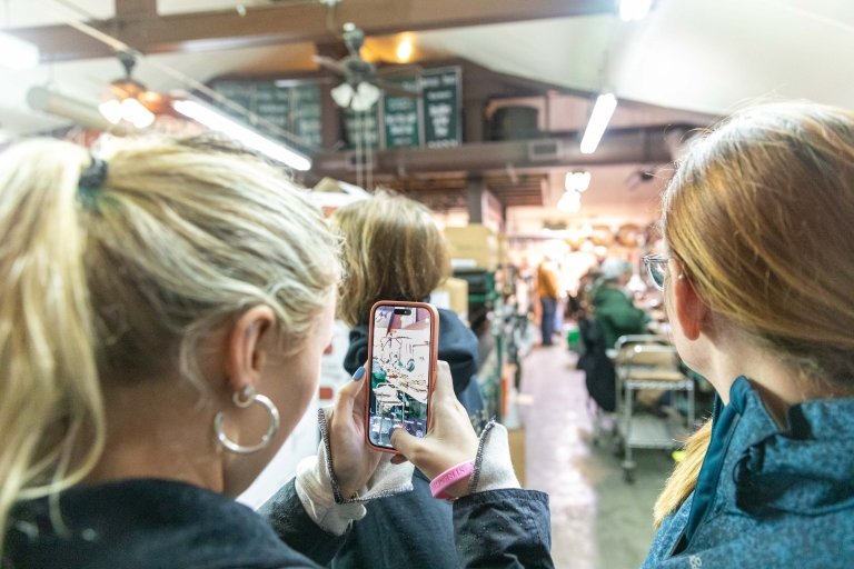 A woman uses her cell phone to photograph distillery operations during a tour. 