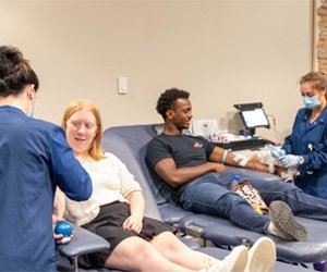 students participating in a blood drive having their blood drawn by nurses