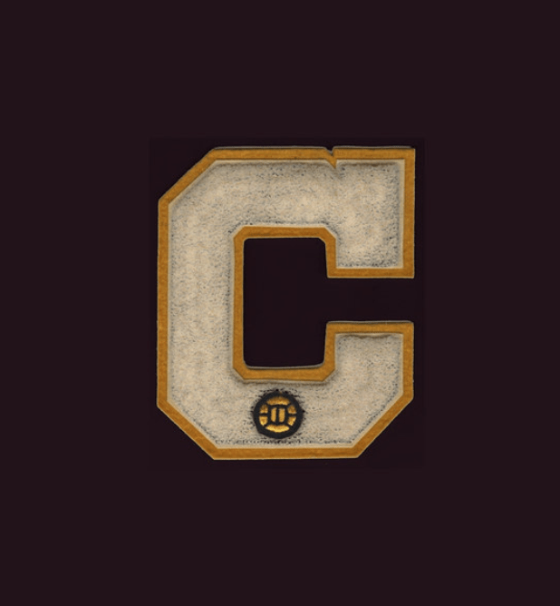 A weathered, stitched patch in the shape of a C bears the image of a soccer ball at the bottom. Part of a letter sweater. 