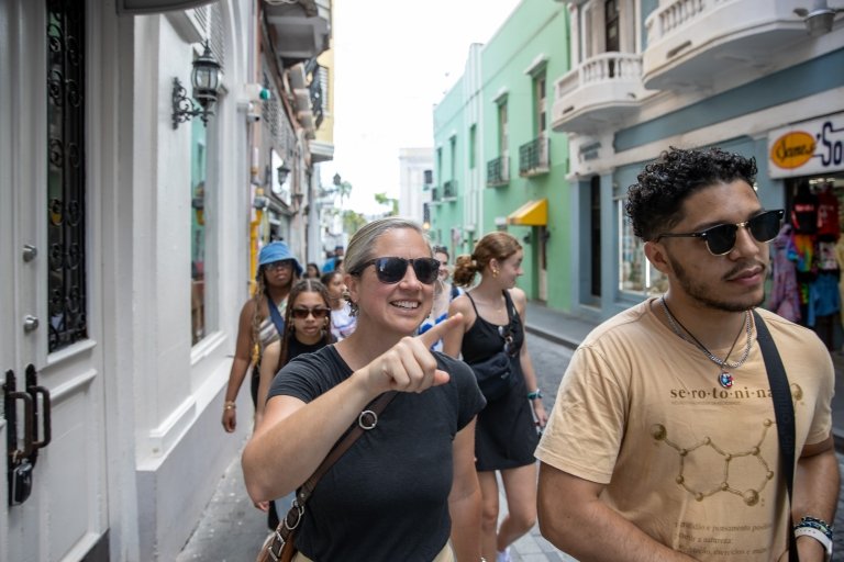 A woman points the way ahead as she walks next to a student down a brightly colored street in Puerto Rico.