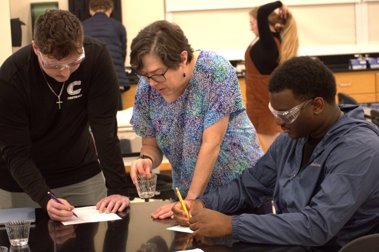 Jennifer Muzyka and two students examine their experiment to see if glass disappeared in a cup. 