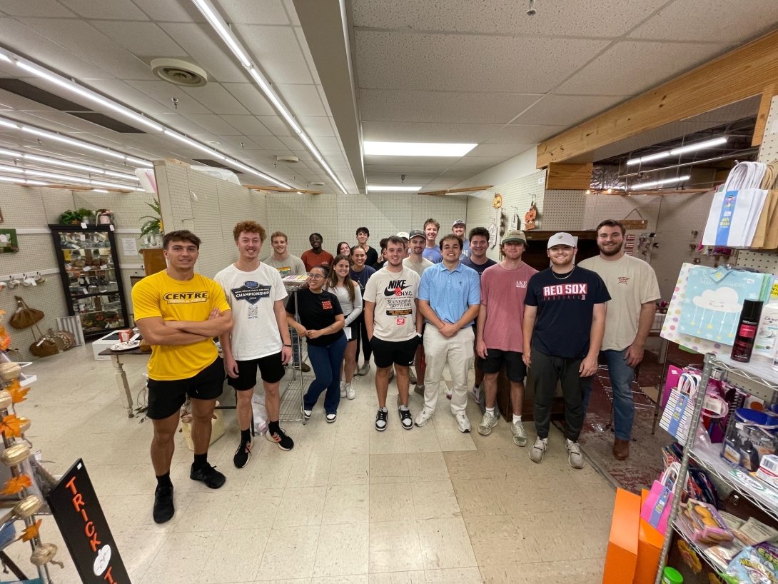 A group of students pose for a photo in a vendor's stall store. 