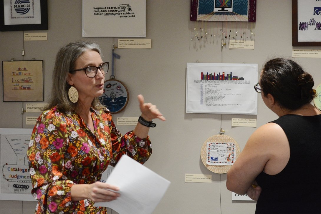 Beth Morgan ’01 talks about the Unseen Labor exhibit at Centre’s Grace Doherty Library as students and staff examine the work on display.  