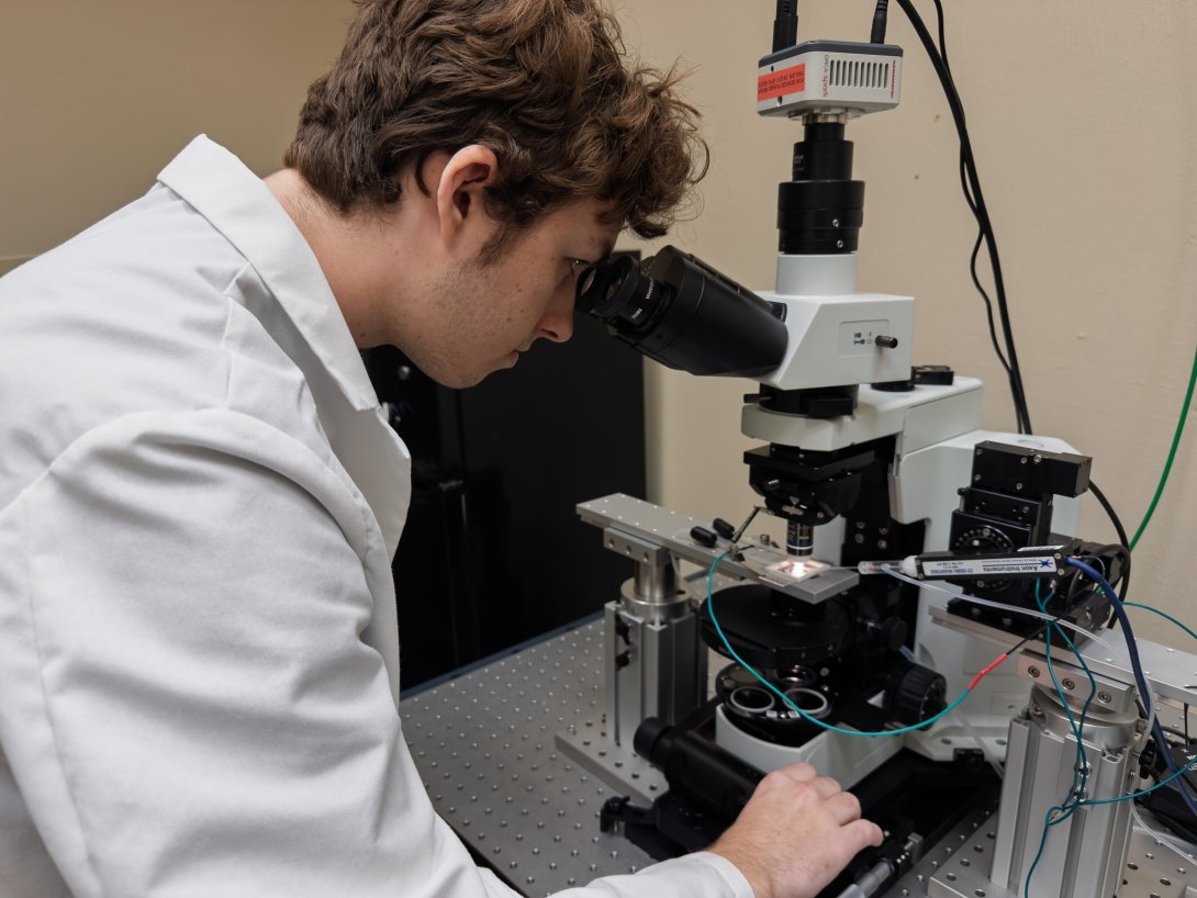 Simon Forsting is looking through a microscope, which is part of his patch-clamp rig.