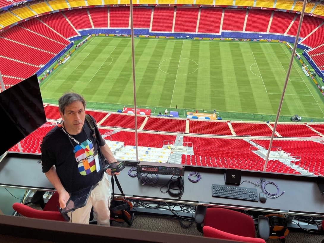 Dave standing behind an IT desk, with the Kansas City field behind him.